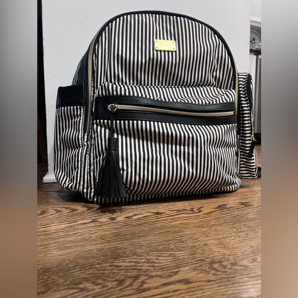 Black and white striped Carter’s baby backpack with gold accents and zipper
